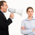 Portrait of angry boss shouting at his secretary through megaphone who is indifferent to it